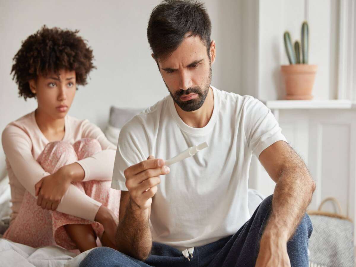 Contraception fail and unwanted pregnancy concept. Frustrated young family couple check pregnancy test.